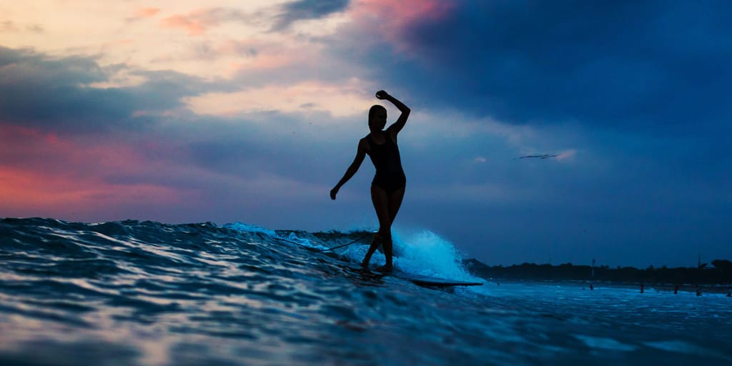Woman on surfboard at sunset